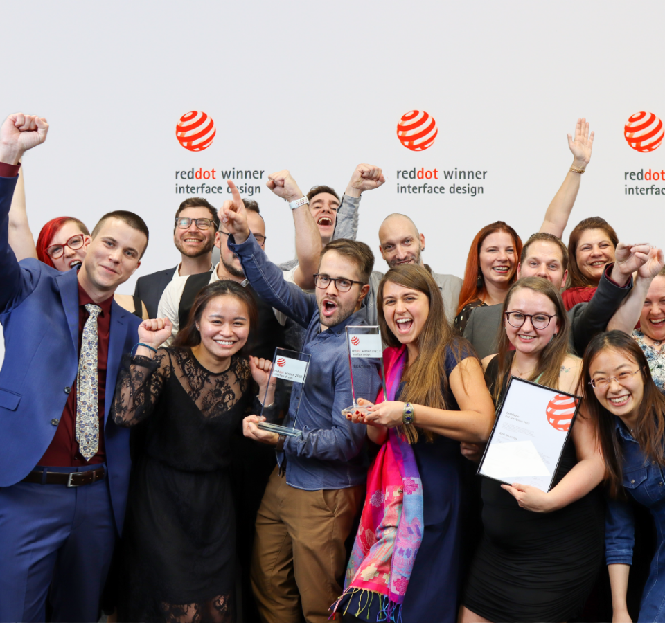 Das Custom Interactions Team feiert gemeinsam den Sieg des Red Dot Design Awards und jubelt.